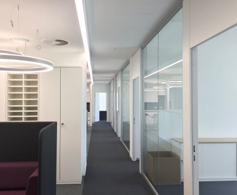 Büroflur mit modernen Glastüren und hellem, minimalistischem Design.
