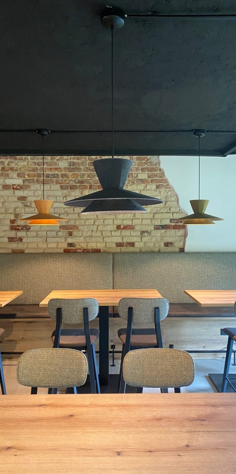 Wandleuchte wirft Schatten auf eine moderne Ziegelwand und Holzverkleidung.