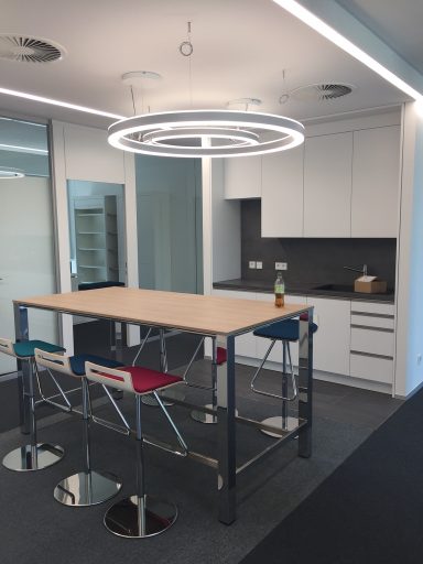Moderne Büroküche mit einem Tisch, Stühlen und heller Beleuchtung.