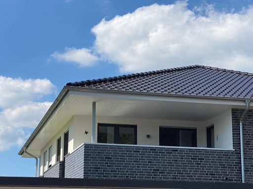 Haus mit modernem Design, Flachdach und Steinverkleidung unter blauem Himmel.