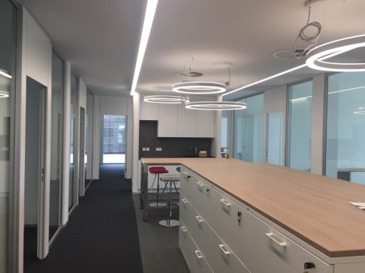 Moderne Büroumgebung mit Holzschreibtisch und Glaswänden. Helle Beleuchtung.